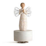 Femal angel figure in cream dress carved with a tree design and wire wings, holding hands in prayer position, standing atop round, cream wood base