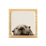 A square wood plaque with a white tile that has an image of an otter.