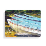 A 24 piece postcard puzzle with a watercolor image of boats on a beach.