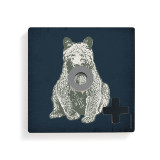 A dark blue square board with a bear for tic tac toe with a gray O piece and a black X piece.