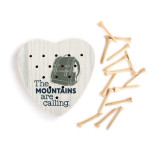 A light wood heart shaped peg game with a green backpack and the saying "The Mountains are Calling" next to a group of wood pegs.