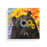 A square wood tic tac toe board with a painted image of a black bear with sunflowers, with a gray O and black X on top.