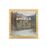 A square wood plaque that has a tile with a mountain stream and says "Where America is still Wild".