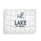 A rectangular wood 24 piece postcard puzzle with a blue Adirondack chair and the saying "Lake it Easy".