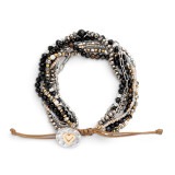 An adjustable bracelet made of multiple stands of various black and silver beads and a mixed metal charm with a gold heart.