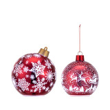 Two different red round ornaments. The large one has white snowflakes and the small has a scene of Santa in his sleigh over the town.
