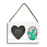 A rectangular hanging white wood frame ornament with a graphic image of a green cactus with pink flowers and a 2x2 heart shaped opening for a photo.