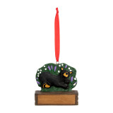 An ornament of a black bear laying in a field of wildflowers, hanging from a red ribbon. There is a spot in front for customization.