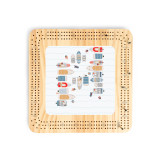 A light wood cribbage board with an illustration of boats in a cove in the center.