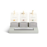 A gray wood tabletop slotted displayer with an assortment of bemindful bracelets in packaging.