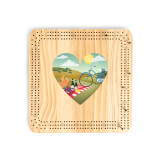 A light wood cribbage board game with heart shaped graphic artwork depicting a wine and cheese picnic on a hillside in the middle.