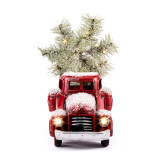 A snowy old fashioned red pickup truck with an evergreen tree in the back.