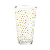 A clear pint glass with a bright colored confetti pattern.