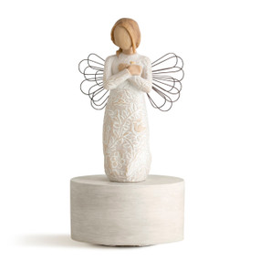 Figure in cream dress carved with natural symbols with wire wings and hands crossed under small gold heart, standing on round cream base