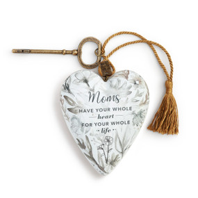 An ivory floral print art heart with a mom sentimental message, a gold tassel, and a bronze key.