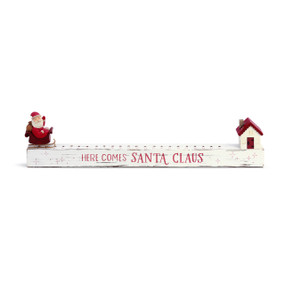 A long white wooden board with holes to move Santa from one end to the house at the other
