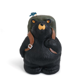 A black bear figurine wearing a green backpack with a little bluebird perched on top.