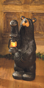 Small black bear figurine holding lantern