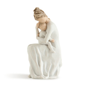 Left view of female figure in white dress sitting on taupe pedestal holding an infant, also wearing white, to her chest