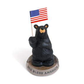 A small figurine of a black bear holding an American flag, The base of the figurine says "God Bless America".