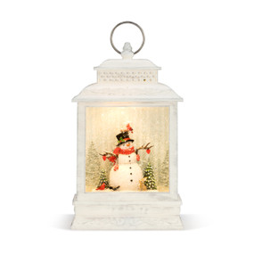 An illuminated white washed wooden musical lantern, with a snowman, Christmas trees, and snow enclosed. With a silver ring.