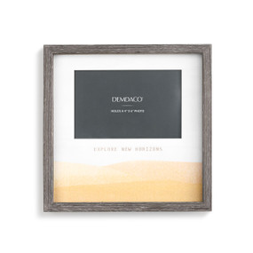 A gray picture frame with a painted yellow plain scene and "explore new horizons" engraved.