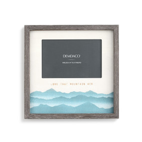 A gray picture frame with a painted blue mountain scene and "love that mountain air" engraved.