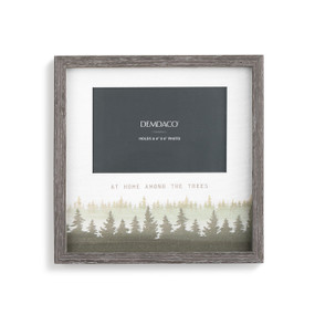 A gray picture frame with a painted brown and green forest scene and "at home among the trees" engraved.