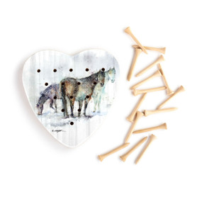 A heart shaped wood peg game with a watercolor painting of three horses, next to a set of wood pegs.