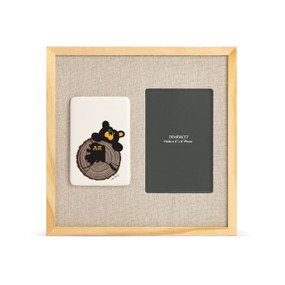A light wood frame with a tile on the left that has a drawn black bear looking over a tree stump with the state of Alaska on it next to a 4x6 photo opening with a linen mat.