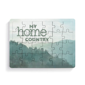 A 24 piece postcard puzzle that says "My home country" on a green mountain background.