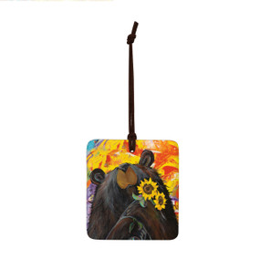 A square ceramic hanging ornament with a painting of a bear holding sunflowers.