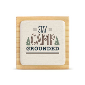 A light wood square plaque with a bone tile attached that says "Stay Camp Grounded".