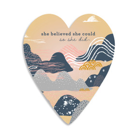 A heart shaped 100 piece puzzle of an abstract drawing of mountains that says "she believed she could so she did".