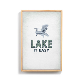 A graphic image of a blue Adirondack chair with "Lake It Easy" written below on a light gray background. The image is in a light wood frame.