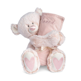 A light pink teddy bear with a pink nose and pink hearts on its paws holding a rolled soft pink blanket that says "loved".