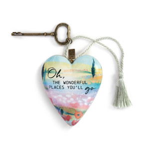 A heart shaped sculpture with a gold key and silver tassel featuring artwork created by ArtLifting artist Midori of an abstract field of poppies and says "Oh, The Wonderful Places You'll Go".