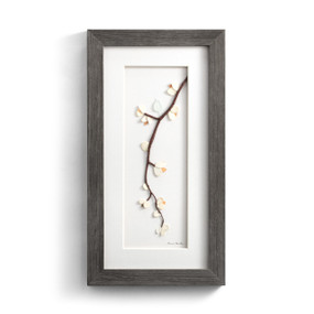 A gray wood framed image of a tree branch with a bird and flowers made of pebbles.