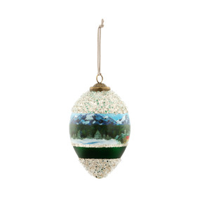 An onion shaped hanging ornament with an image of a winter Swiss Chalet around the middle and silver glitter around the top and bottom inspired by artwork from ArtLifting artist Lucas Farlow.
