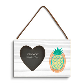 A rectangular hanging white wood frame ornament with a graphic image of a yellow pineapple on an orange background with a 2x2 heart shaped opening for a photo.