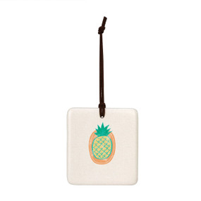 A square hanging tile ornament with a graphic image of a yellow pineapple on an orange background.