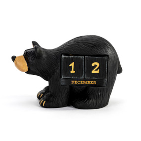 A perpetual calendar made of two number blocks and a month block that fit into the side of a standing black bear figurine.