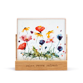 A square oil diffuser with a watercolor image of colorful wildflowers on it set in a wood stand that says "relax, renew, refresh".