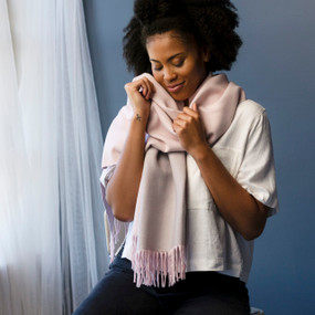 A woman wearing a fringed pink giving wrap shawl.