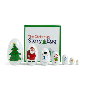 A set of seven nesting eggs with different Christmas images on them, lined up in front of a book titled "The Christmas Story Egg".
