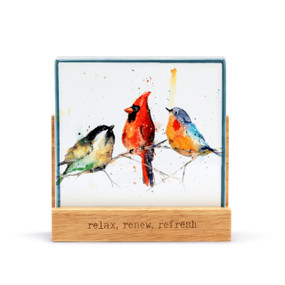 A square oil diffuser with a watercolor image of three songbirds on a branch on it set in a wood stand that says "relax, renew, refresh".