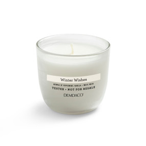 A white tester candle in a clear glass container with a winter wishes scent.