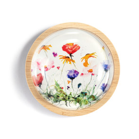 A light wood round paperweight with a glass dome over a watercolor image of wildflowers.