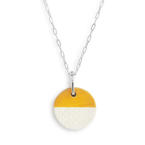 Detail view of the charm on an adjustable silver chain necklace with a circle shaped gold and white diffuser charm.