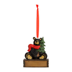 A hanging ornament with a sitting black bear in a red scarf and holding a pine tree on a rectangular base that can be personalized.